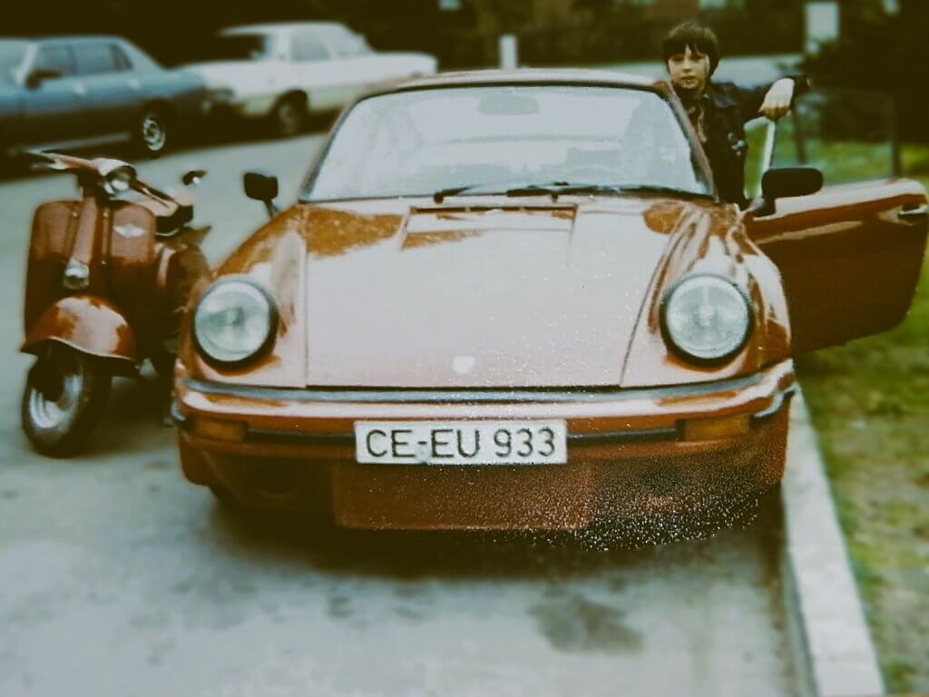 Uwe Weinreich in jungen Jahren an einem alten roten Porsche 911, der damals seinen Eltern gehörte.