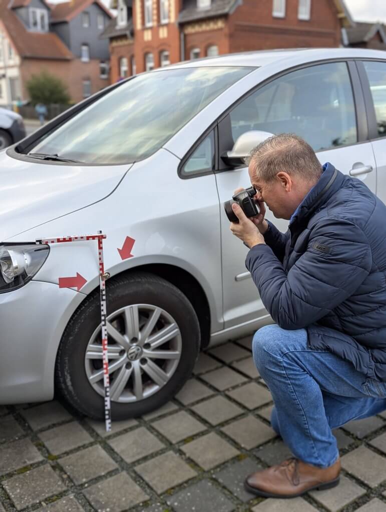 Der Kfz Gutachter Uwe Weinreich aus Garbsen fotografiert einen Unfallschaden an einem silbernen VW Golf Plus